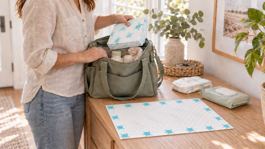 Illustrative scene of a parent packing turtle-print disposable changing pads into a diaper bag beside an unfolded pad.