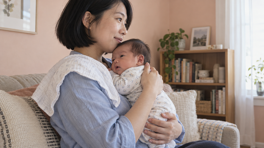 A mother supporting her awake newborn upright against her chest after a feed.